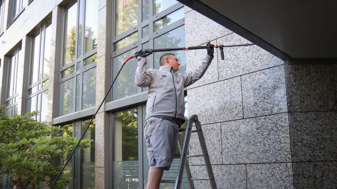 Ein Mitarbeiter reinigt eine Fassade mit einem Hochdruckreiniger