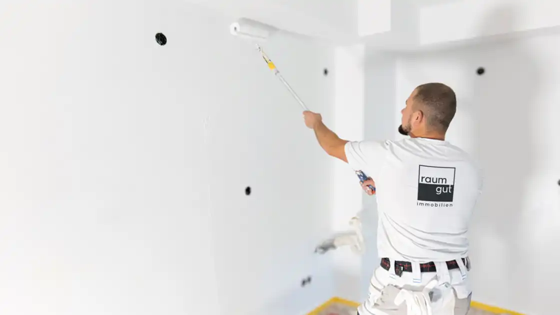 Ein Maler beim Streichen einer Wand