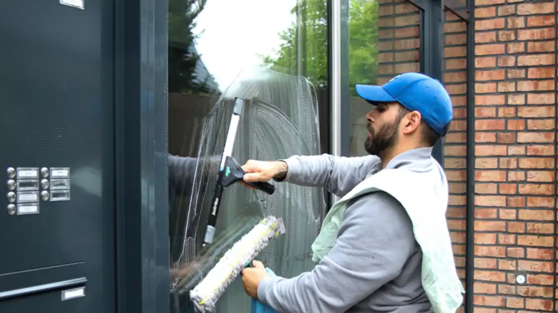 Ein Mitarbeiter von raumgut beim Reinigen einer Glastür