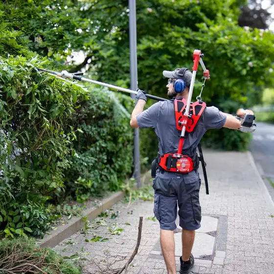 Mitarbeiter des raumgut Facility Teams bei der professionellen Gartenpflege und beim Schneiden einer Hecke in Düsseldorf.