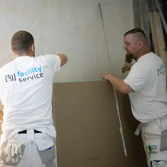 Zwei Handwerker arbeiten an einer Wand