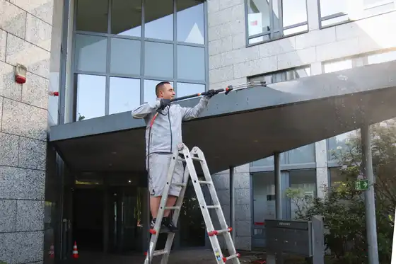 Ein Mitarbeiter reinigt ein Vordach mit einem Hochdruckreiniger