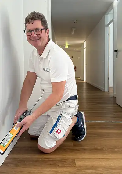 Ein Mann mit einer Kartuschenpresse vor einer Fußleiste